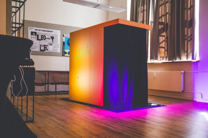 Walk-in photo-booth style installation of ANA, with screens showing the AI storytelling interface and emotion recognition feedback